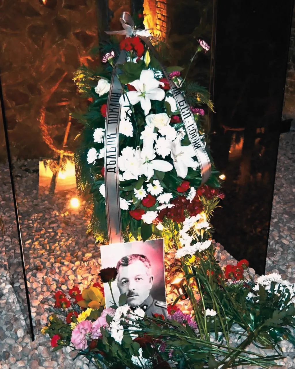 Членове на БКМС са застанали пред паметник с цветя и венци в основата. Групова снимка на открито.